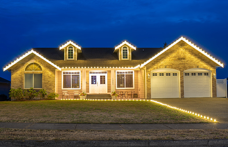 Warm white lighting across a roofline and along a pathway