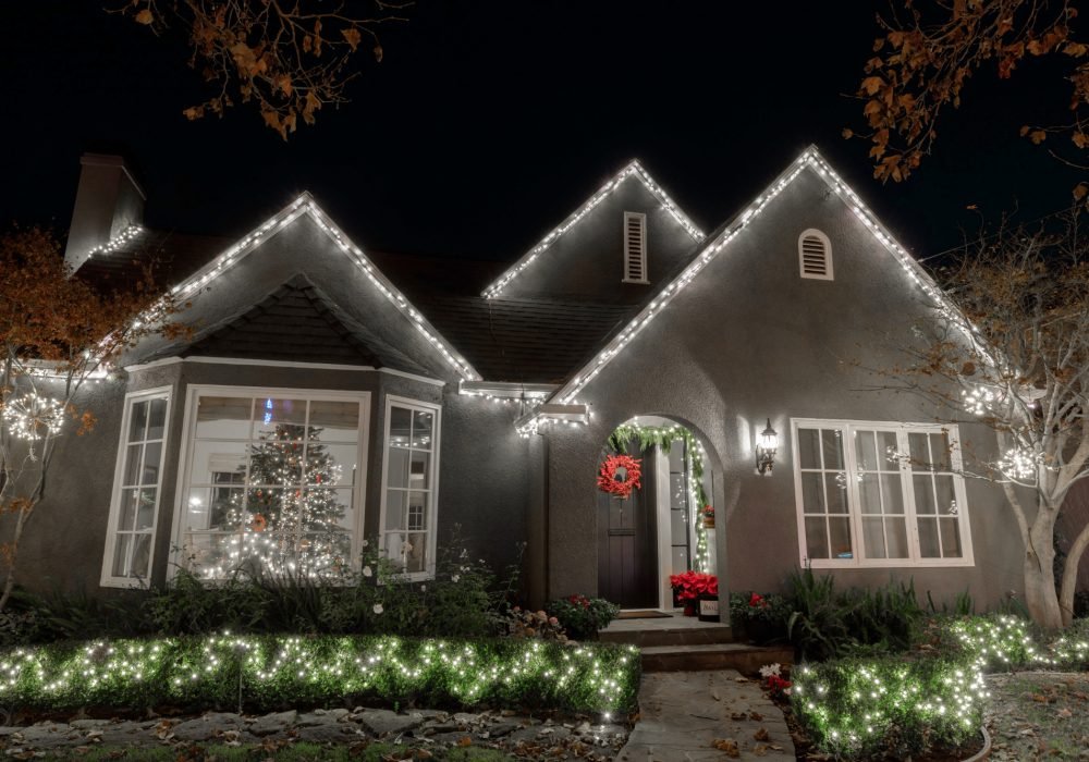 Wonderland website display with lit roofline, wreath, and illuminated hedges